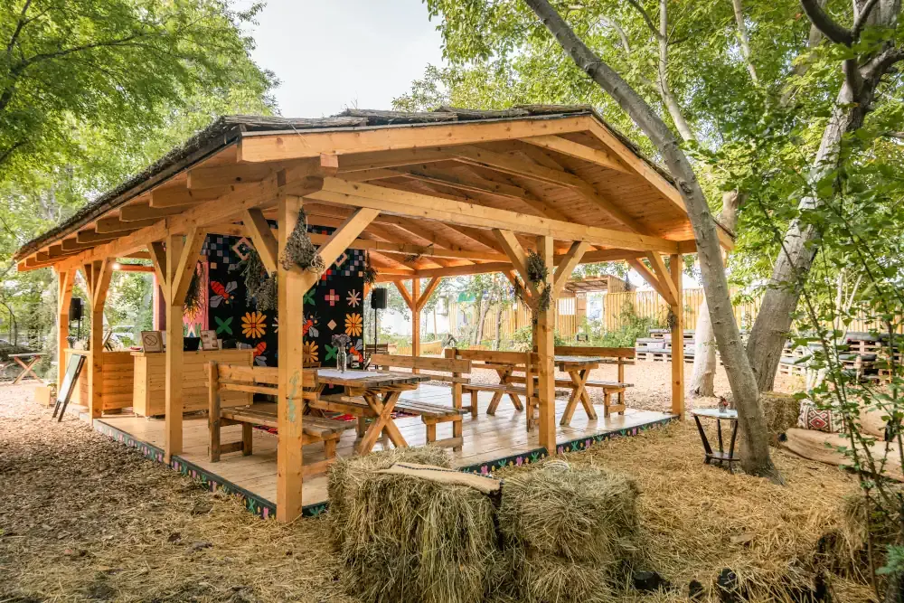 BeeFe bar: drvena nadstrešnica sa klupama i stolovima, bale sena i oslikan zid iza njih