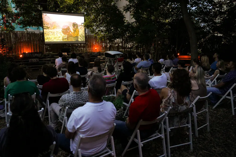 Noćni bioskop na otvorenom, platno razapeto među drvećem