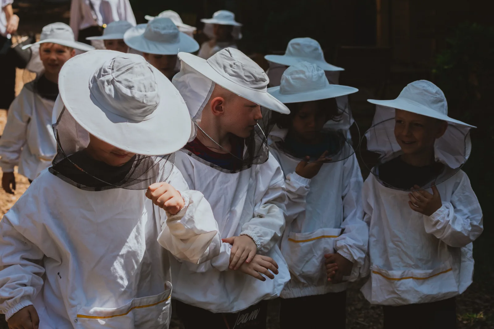 Children in beekeeping suits with hats and veils, photographed close up in the garden