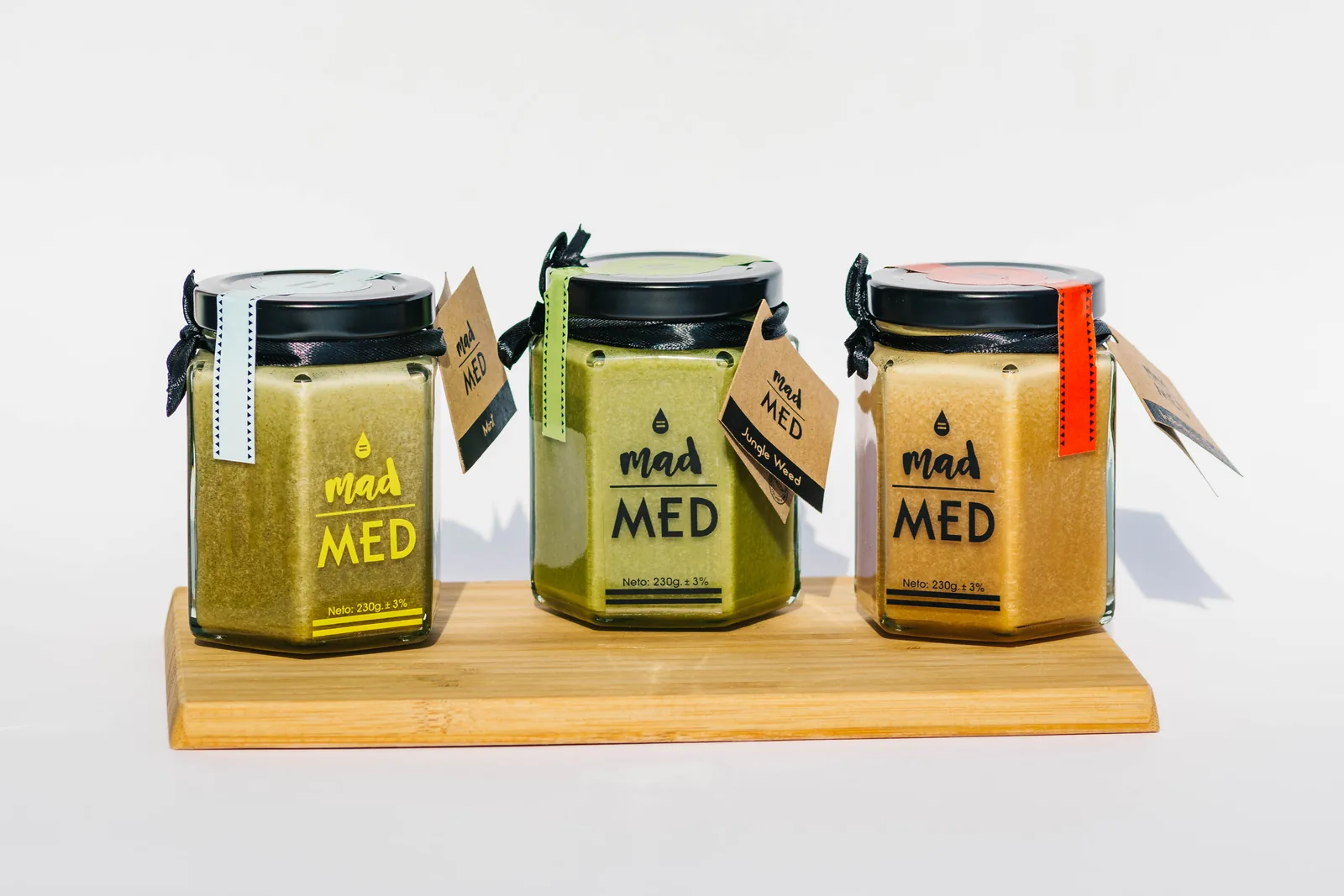 Tri tegle MadMed meda različitih sorti na drvenoj dasci